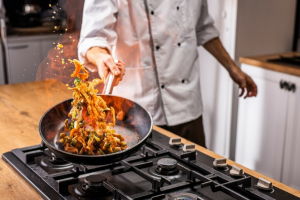 Chef demonstrating techniques taught in Culinary and Hospitality Courses, preparing a gourmet dish in a professional kitchen